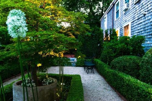 einen Garten mit einem Baum und einer Bank und einem Gebäude in der Unterkunft Union Street Inn in Nantucket