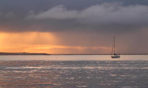 a sailboat in the water with a rainbow in the sky at Anchorage Seafront Hotel in Victor Harbor