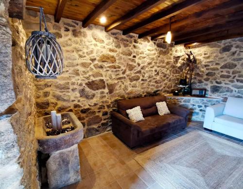 sala de estar con sofá y pared de piedra en Apartamentos Casa do Bouza Vello, en Sober