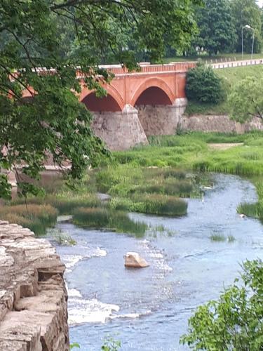 a bridge over a river with a rock in the water at Maza Venecija-Kuldiga in Kuldīga