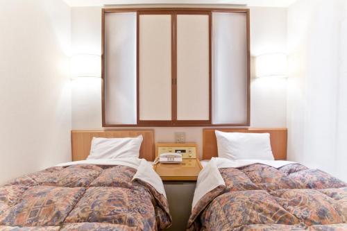 dos camas sentadas una al lado de la otra en un dormitorio en Kuretake-Inn Hamamatsu Nishi I.C., en Hamamatsu