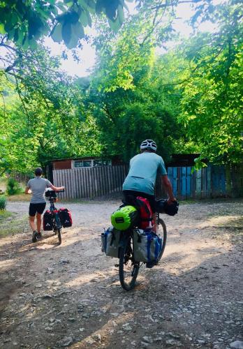 a man riding a bike down a dirt road next to a person at Butichi Guest House in Chiatʼura