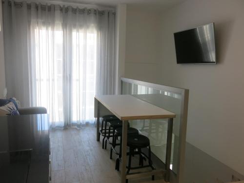 a dining room table with chairs and a television on a wall at SERENA BEACH 3 in Nazaré