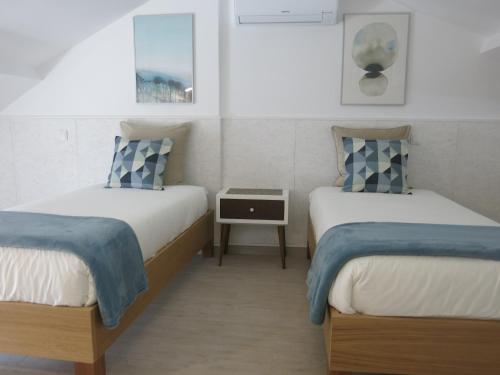 two twin beds in a room with a table at SERENA BEACH 3 in Nazaré