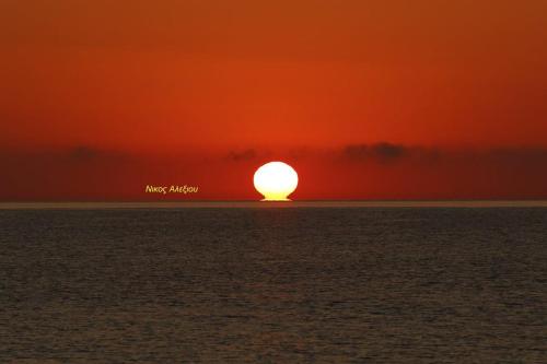 a sunset over the ocean with the sun in the sky at Θέα - View Appartments in Paralía Kímis