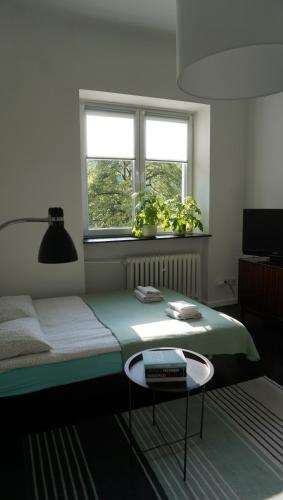 a bedroom with a bed with a table and two windows at Lovely Bubbly Apartment in Krakow