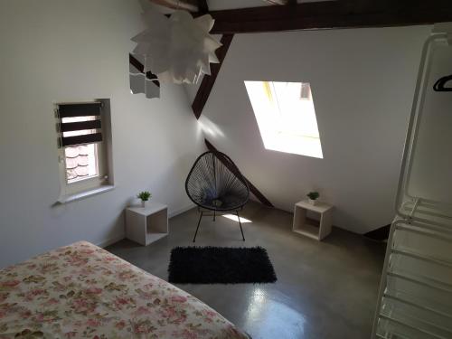 a bedroom with a bed and a chair and a window at La Grande Terrine - Gîtes Les Potiers in Kaysersberg