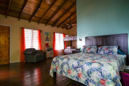 a bedroom with a bed and a chair and windows at Casita Océana in Sandy Bay