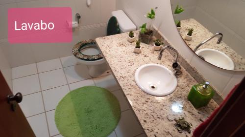 a bathroom with two sinks and a toilet with a green rug at Residencia Bali Bahia in Praia do Forte