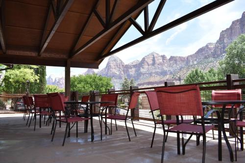 a group of chairs and tables with mountains in the background at Zion Canyon Lodge in Springdale
