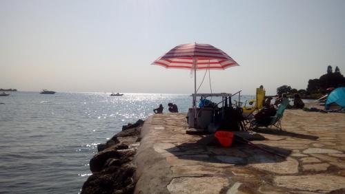 a beach with an umbrella and chairs on the water at Apartman Sole in Karigador