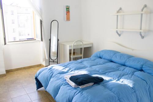 un grande letto blu in una stanza con finestra di Confortevole Appartamento a pochi passi dal Centro ad Alghero