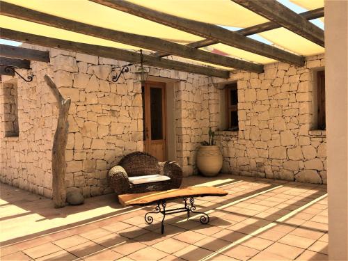 a chair sitting on a patio with a stone wall at Casa Bedda in Noto Marina