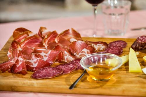 a cutting board with cured meat and a glass of wine at AGRITURISMO LA VALLE DEI BRONZETTI in Cascia