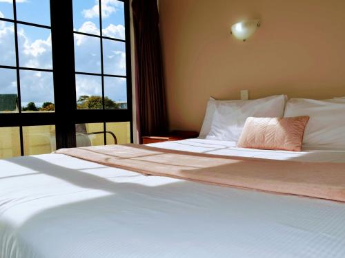 a bedroom with a large bed with a large window at Salty Dog Inn in Snells Beach