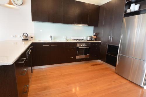 a kitchen with black cabinets and a stainless steel refrigerator at Apartment K2 06 AMS Mt Buller in Mount Buller