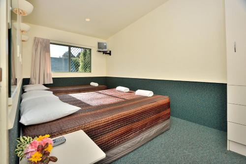 a bedroom with a bed and a table and a window at Auckland Northshore Motels & Holiday Park in Auckland