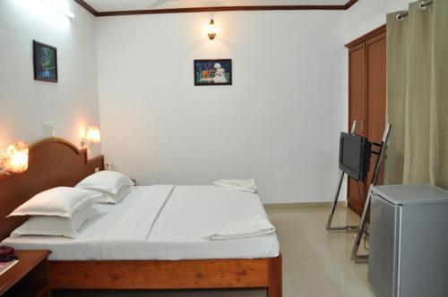 a bedroom with a bed and a television in it at Sayoojyam Residency in Palakkad