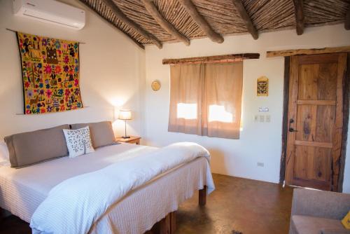 ein Schlafzimmer mit einem weißen Bett und einem Fenster in der Unterkunft El Pedregal - Hotel en la Naturaleza in Álamos