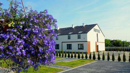 una casa bianca con fiori viola di fronte di Hotel Sjesta a Nowa Sól