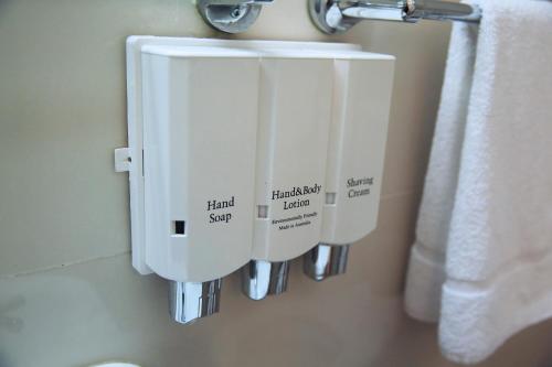 a bathroom with two soap dispensers on a wall at Ryde Inn in Sydney