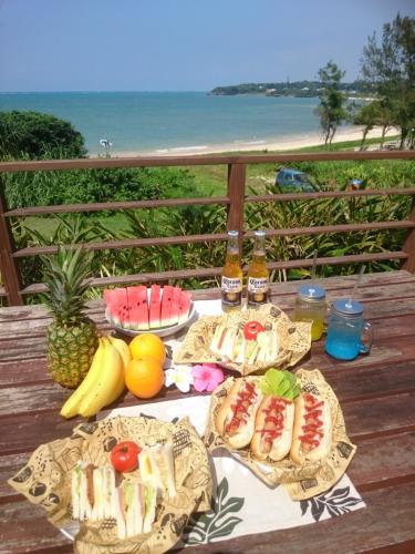 a table with plates of food and fruit on a balcony at Private Beach House in Motobu
