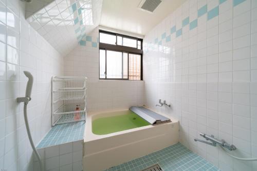 La salle de bains est pourvue d'une baignoire verte et d'une fenêtre. dans l'établissement Ryokan Nakadaya, à Tokyo