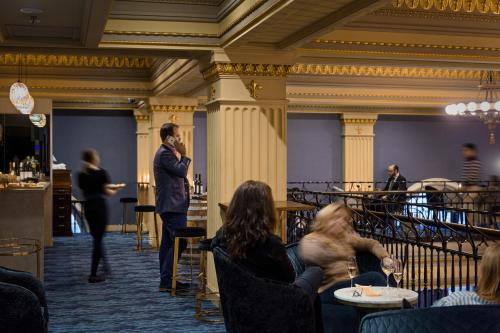 a man talking on a cell phone in a restaurant at Treasury on Collins Melbourne in Melbourne