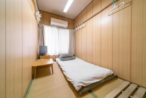 Mały pokój z łóżkiem i biurkiem z telewizorem w obiekcie Ryokan Nakadaya w Tokio