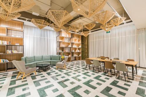 a library with a green couch and tables and chairs at Atour Hotel (Tongxiang Zhenxing Road) in Tongxiang