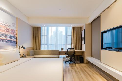a hotel room with a bed and a flat screen tv at Atour Hotel (Tongxiang Zhenxing Road) in Tongxiang