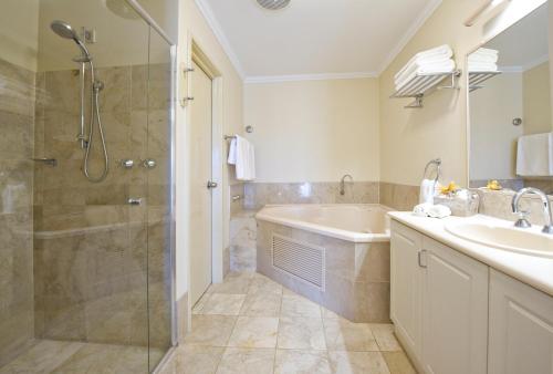 ein Bad mit einer Badewanne, einem Waschbecken und einer Dusche in der Unterkunft Abbey Beach Resort in Busselton