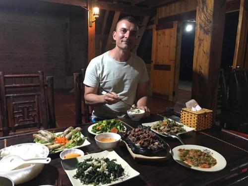 a man sitting at a table with plates of food at My's Homestay sapa in Sa Pa