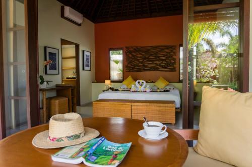 a bedroom with a bed and a table with a hat on it at Villa Sabandari in Ubud