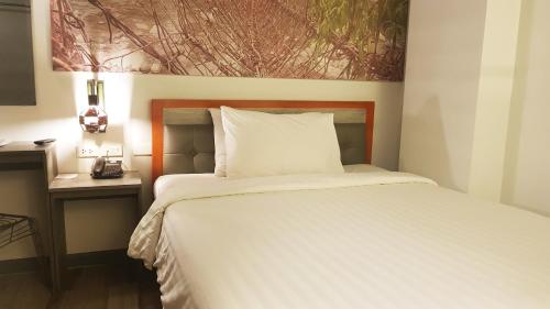 a bedroom with a white bed with a picture on the wall at GQ Plaza in Kalibo