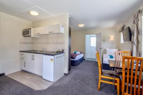 a kitchen and a dining room with a table and a room at Caples Court Motel & Apartments in Queenstown