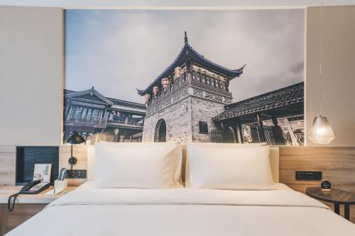 海宁海宁皮革城南关厢亚朵酒店的大楼前的一张带白色枕头的床