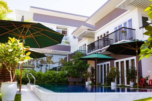 ein Hotel mit einem Pool mit Sonnenschirmen in der Unterkunft Riverside Villa Homestay in Đà Nẵng