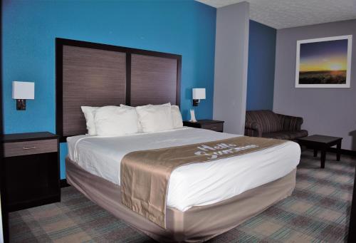 a hotel room with a large bed and a chair at Days Inn by Wyndham Montgomery in Montgomery