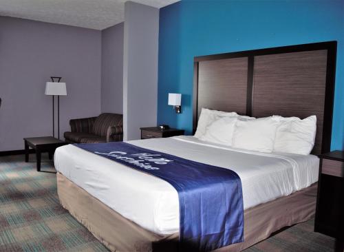 a hotel room with a large bed and a chair at Days Inn by Wyndham Montgomery in Montgomery