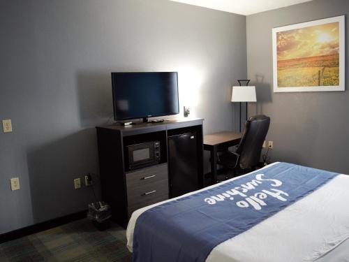 a hotel room with a bed and a flat screen tv at Days Inn by Wyndham Montgomery in Montgomery