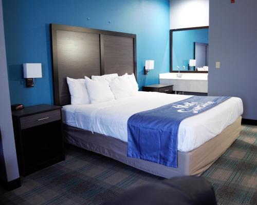 a bedroom with a large bed with a blue wall at Days Inn by Wyndham Montgomery in Montgomery