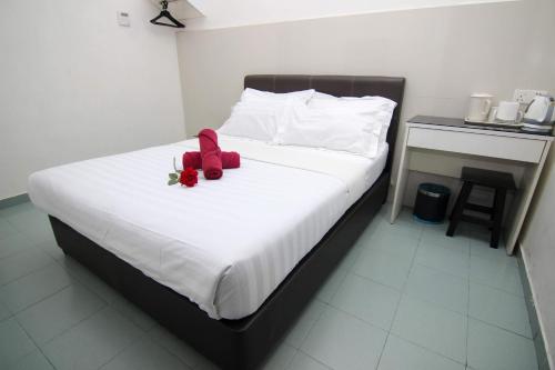 a bed with a red stuffed animal on it at Rose Cottage Hotel Taman Johor Jaya in Johor Bahru