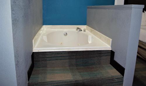 a white bath tub in a room with a blue wall at Days Inn by Wyndham Montgomery in Montgomery