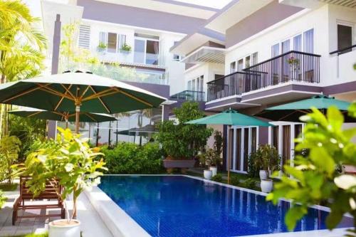 einem Pool vor einem Gebäude mit Sonnenschirmen in der Unterkunft Riverside Villa Homestay in Đà Nẵng