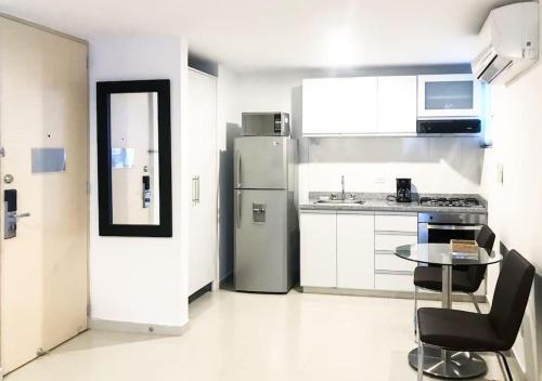 a white kitchen with a table and a refrigerator at Apartamento cómodo en la ciudad bonita in Bucaramanga