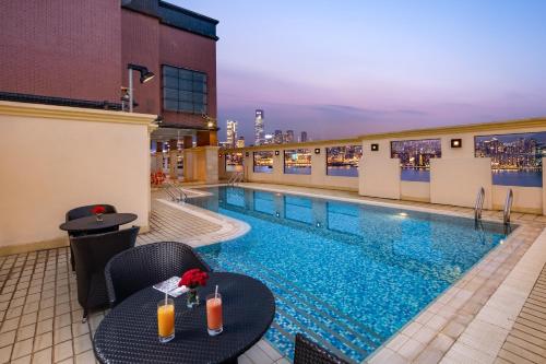 a pool on the roof of a building with tables and drinks at Ramada Hong Kong Grand View in Hong Kong