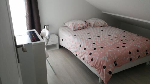 a small bedroom with a bed with polka dot sheets at Les pieds dans l'eau in Arcachon