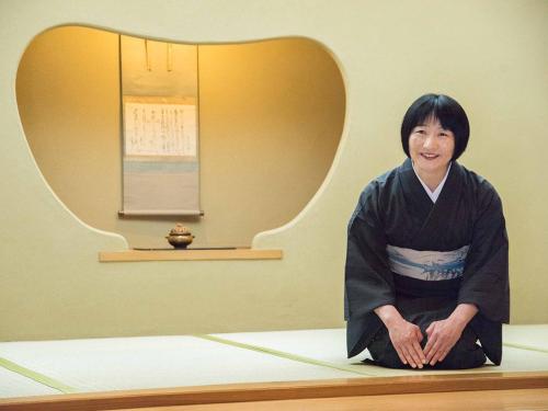 una mujer sentada en una mesa en una habitación en Yamatoya Besso, en Matsuyama