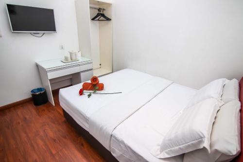 a white bed with a teddy bear sitting on top of it at Rose Cottage Hotel Taman Nusa Cemerlang in Gelang Patah